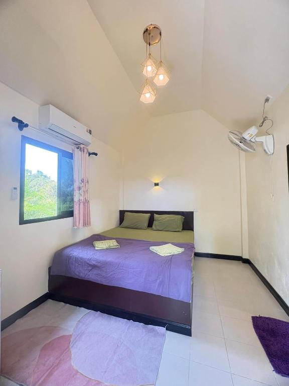 a bedroom with a bed with purple sheets and a window at cher lonely beach resort Koh chang in Ko Chang