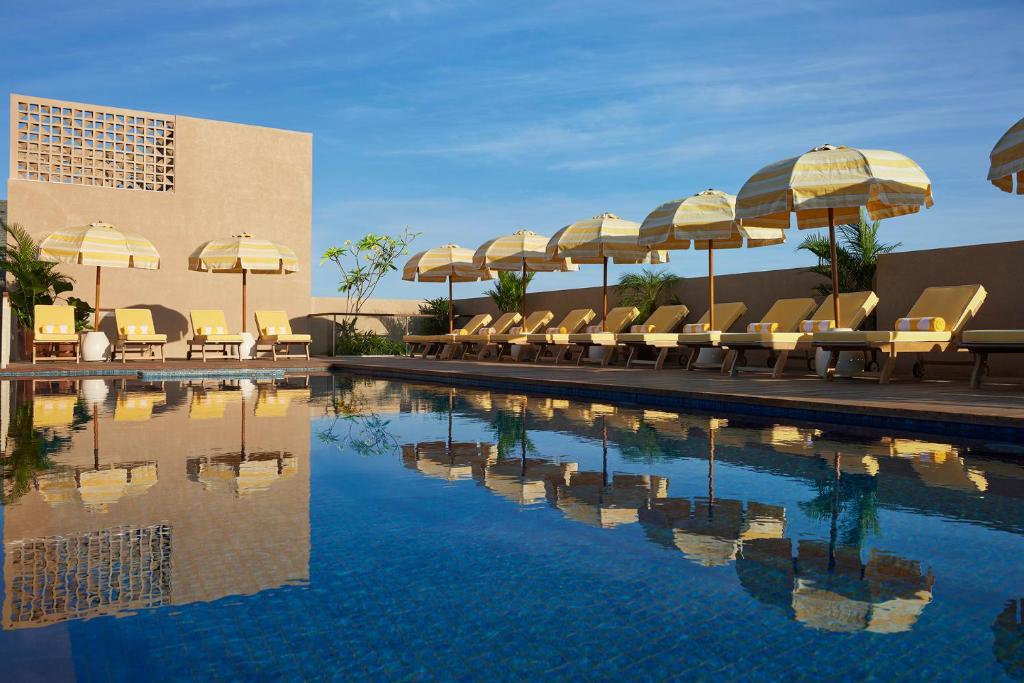 una piscina con sombrillas y tumbonas y una piscina en Kleo Seminyak, part of JdV by Hyatt, en Seminyak