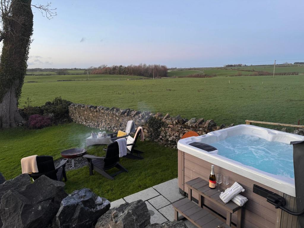 a hot tub in a yard with a table and chairs at Dolwaenydd in Llanfairpwllgwyngyll