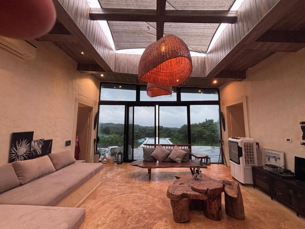 a living room with a couch and a table and a chandelier at Silvaate stay in Karjat