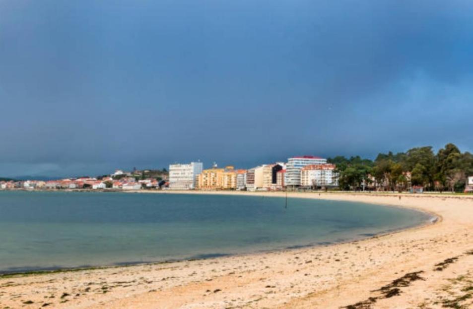 Una vista de una playa con edificios al fondo. en Bruma, en Vilagarcía de Arousa
