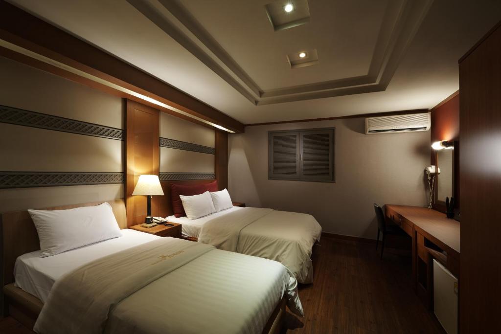 a hotel room with two beds and a desk at Hotel Noblesse, Yeoksam in Seoul