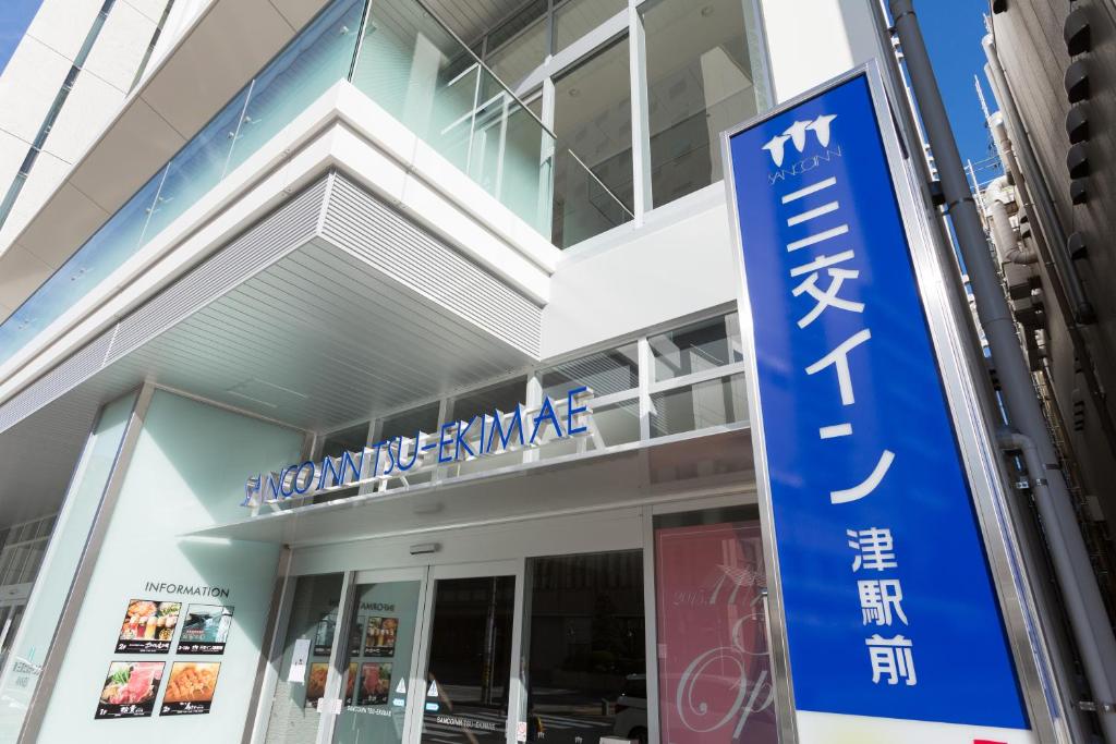 un bâtiment avec un panneau bleu devant lui dans l'établissement Sanco Inn Tsu Ekimae, à Tsu