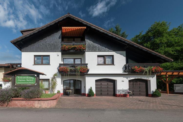 a large white house with two garage at Ferienwohnung Siefert in Mossautal
