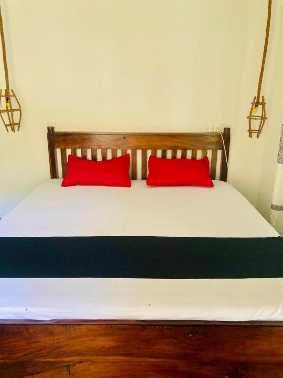 a bed with two red pillows on top of it at Relax point cabana & restaurant in Netolpitiya