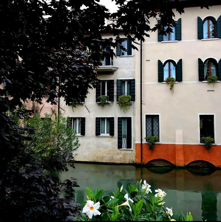 a building with flowers in front of a body of water at B&B San Leonardo in Treviso