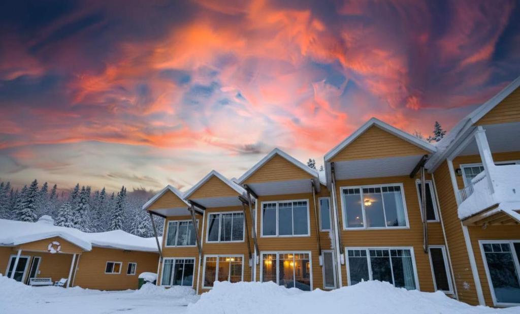 a house in the snow with a sunset at Condo Bord de fleuve Piscine - Les Voitures d'Eau in L'Isle-aux-Coudres