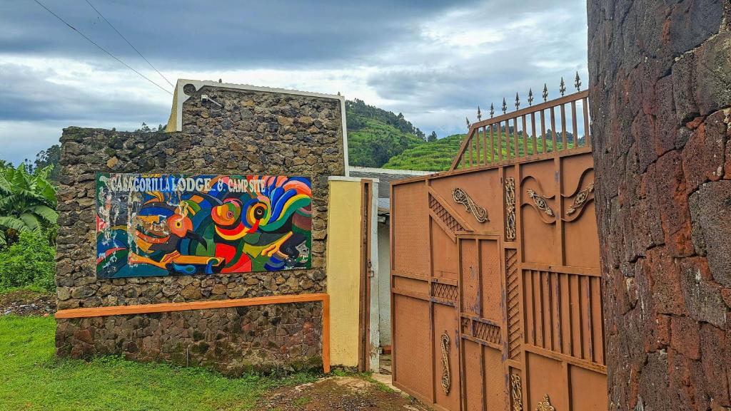 Eine Mauer mit einem Gemälde darauf neben einem Zaun in der Unterkunft New Casa Gorilla Lodge and Campsite in Kisoro