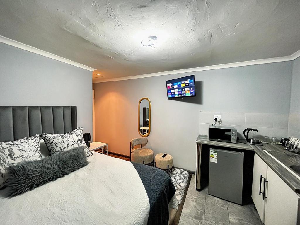 a bedroom with a bed and a kitchen with a tv at Awezi Overnight in Coldstream