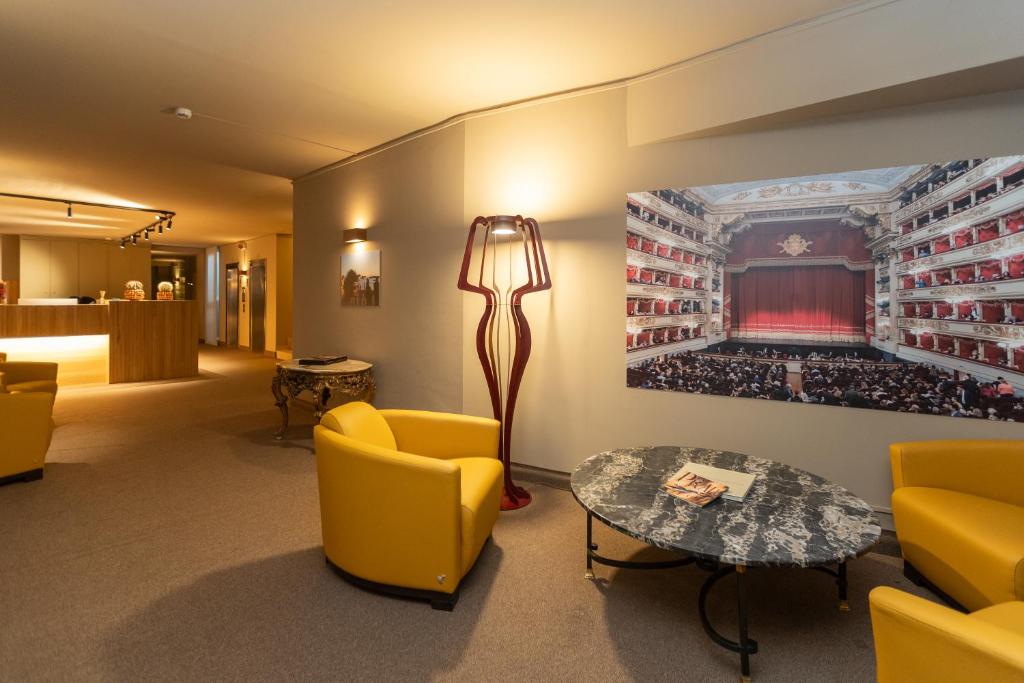Una sala de espera con sillas amarillas y una mesa. en Garibaldi Palace, en Milán