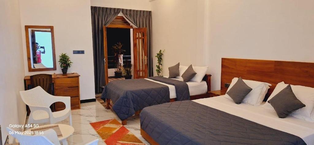 een hotelkamer met twee bedden en een spiegel bij Green inn Trinco in Uppuveli
