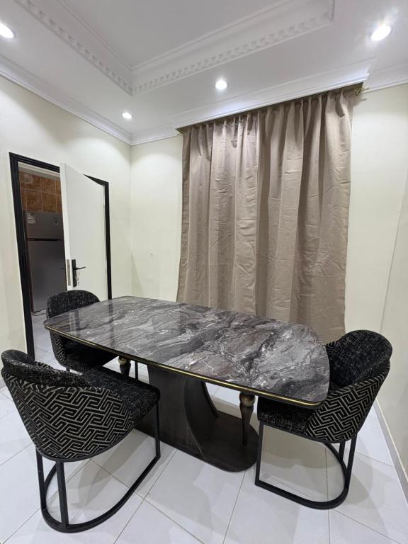 una mesa de mármol y sillas en una habitación en Alzahra residence 4 km to AlHaram, en La Meca