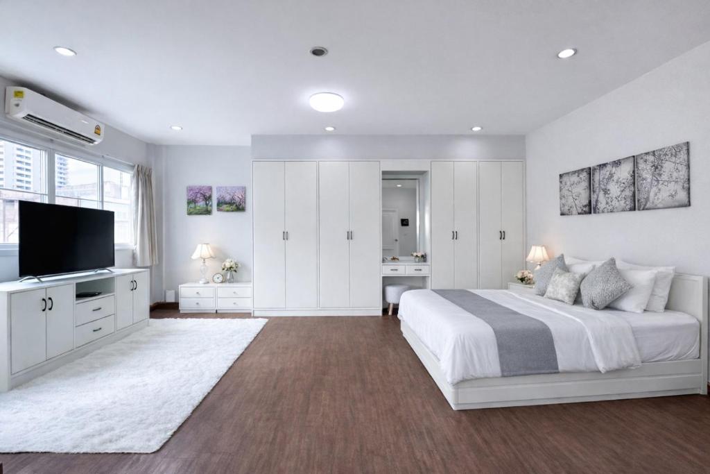 a white bedroom with a bed and a flat screen tv at Blissful Heaven Residence at BTS Phromphong Emdistrict Shopping Area in Bangkok