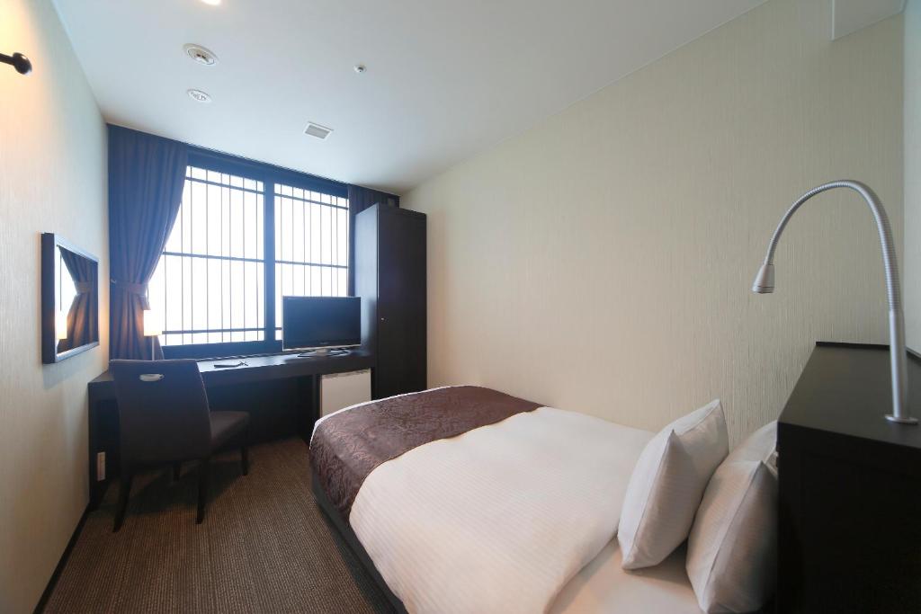 a bedroom with a bed and a desk with a computer at Kyoto Tower Hotel in Kyoto