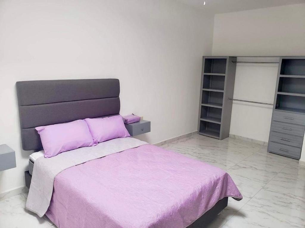 een slaapkamer met een bed met een paarse deken bij Departamento Céntrico in Monterrey