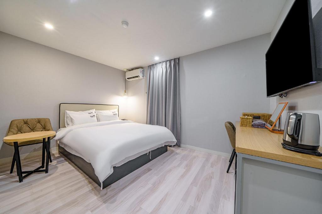 a hotel room with a bed and a desk and a tv at 광안비치호텔더엠 in Kwangan-dong