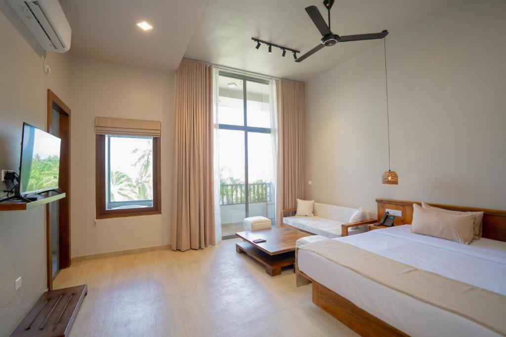 une chambre avec un lit, un canapé et une télévision dans l'établissement Emerald Resort Hikkaduwa, à Hikkaduwa