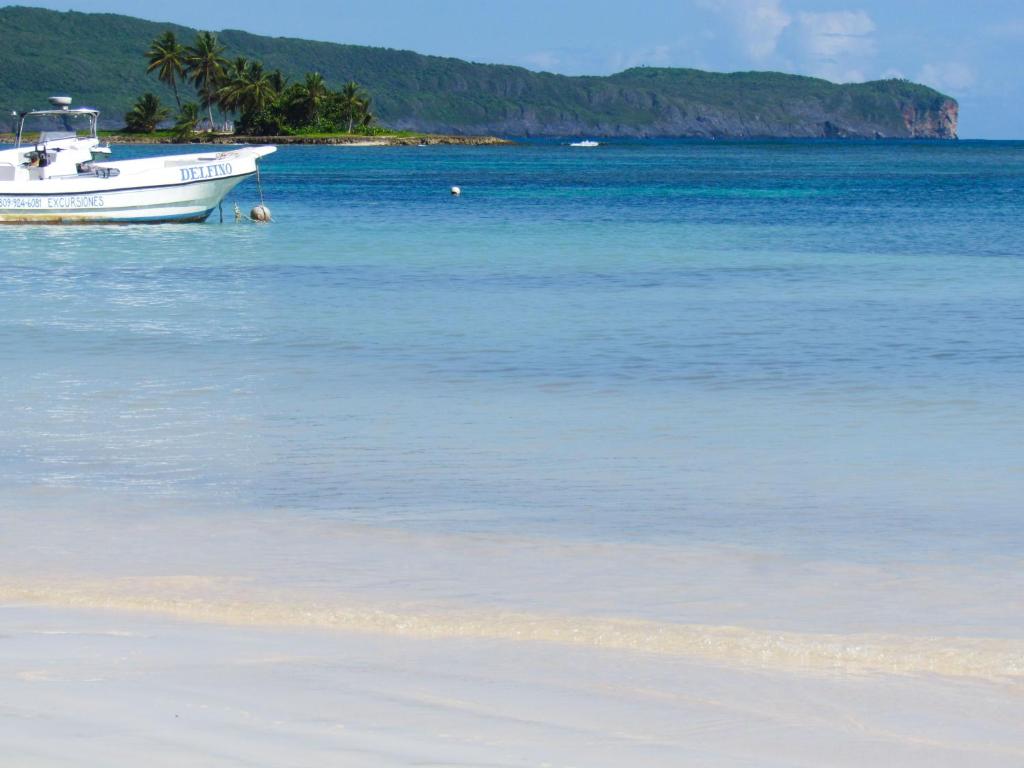 a boat sitting in the water on a beach at Las Galeras Hotel in Las Galeras