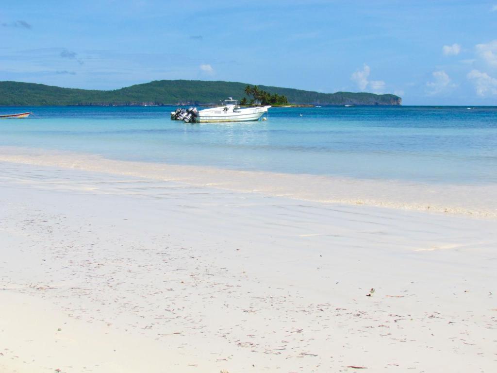 a boat in the water on a beach at Las Galeras Hotel in Las Galeras