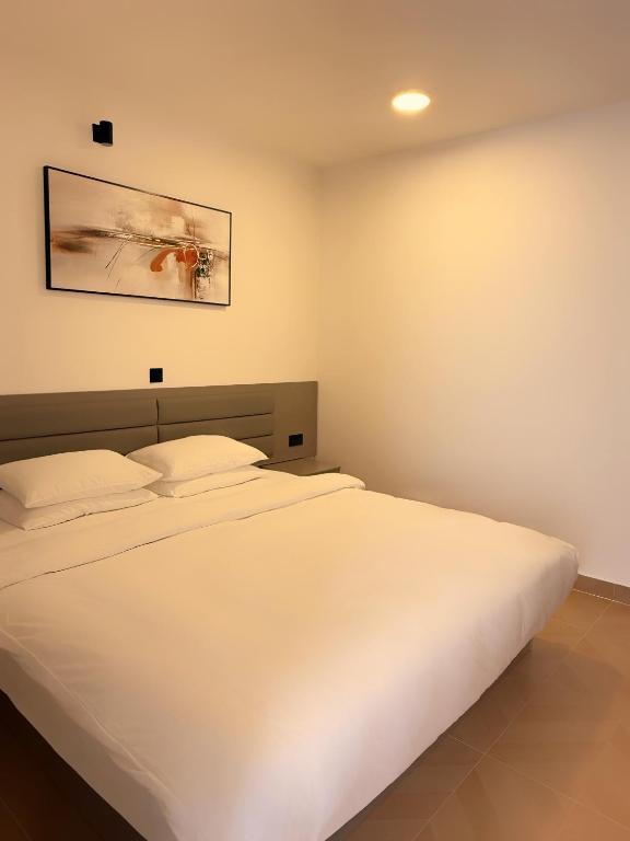 a white bed in a bedroom with a picture on the wall at Manta Beach Retreat in Hikahera