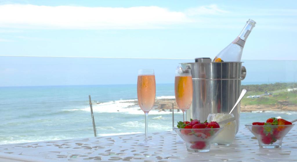 a table with two champagne glasses and a bowl of fruit at La Crete Sands no 3 in Uvongo Beach
