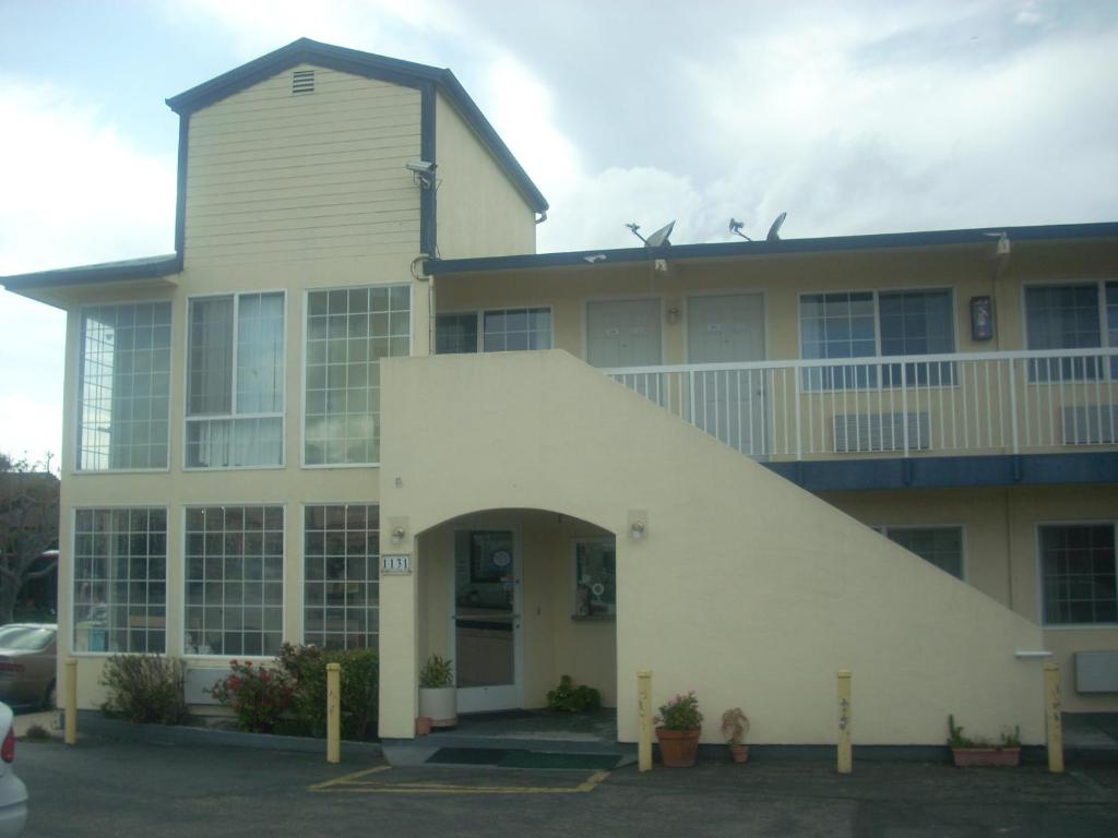 a large white building with an archway in a parking lot at Economy Inn Seaside in Seaside