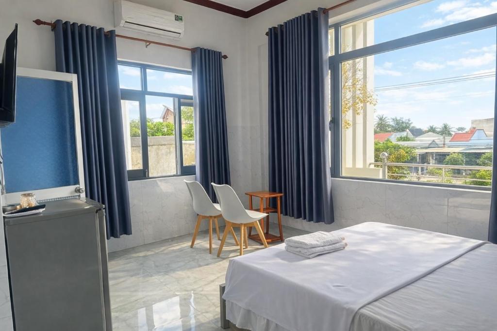 um quarto com uma cama, 2 cadeiras e janelas em Ngọc Nga Hotel em Phan Rang