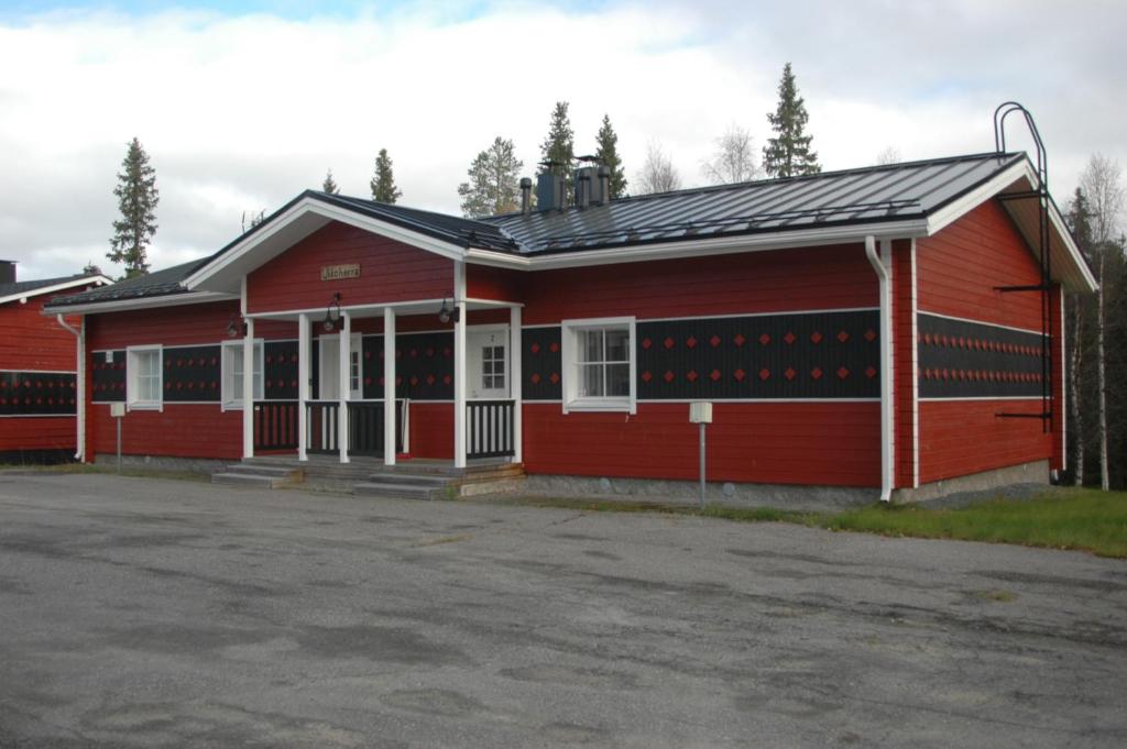 ein rotes Gebäude mit einem Parkplatz davor in der Unterkunft Chalets UkkoHerra 1 & 2 in Ruka
