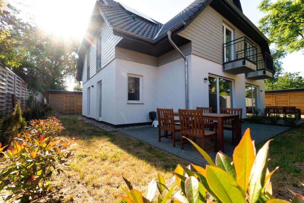 ein Haus mit einer Terrasse mit Tisch und Stühlen in der Unterkunft Ferienwohnungen am Darßer Ort inkl Wäschepaket in Wieck