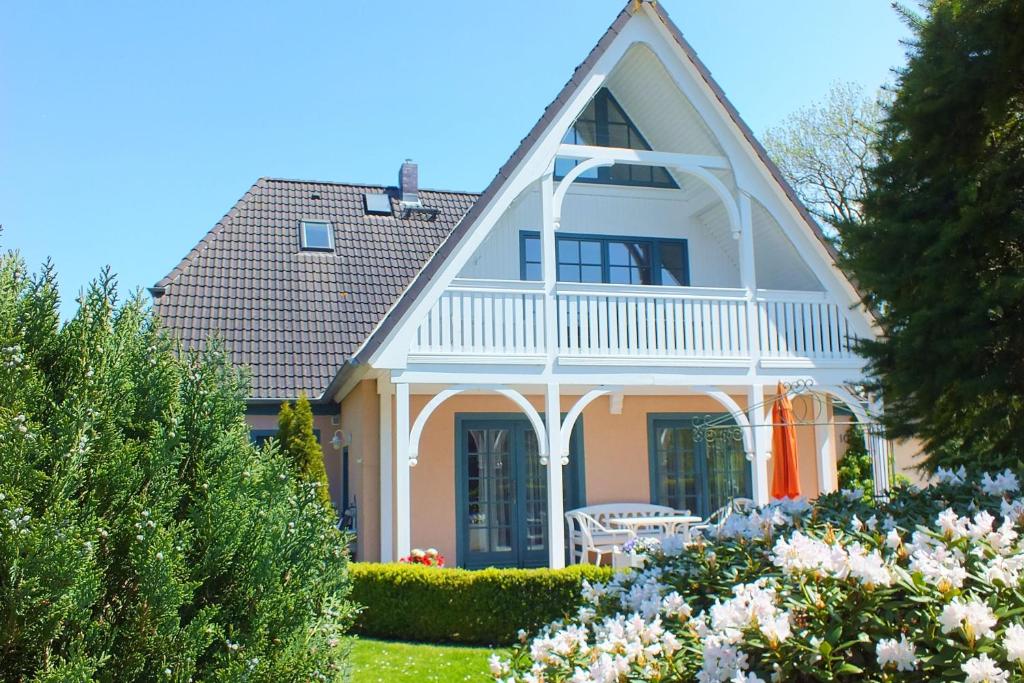a white house with a porch and a lawn with flowers at Ferienwohnungen im Klönhus in Prerow