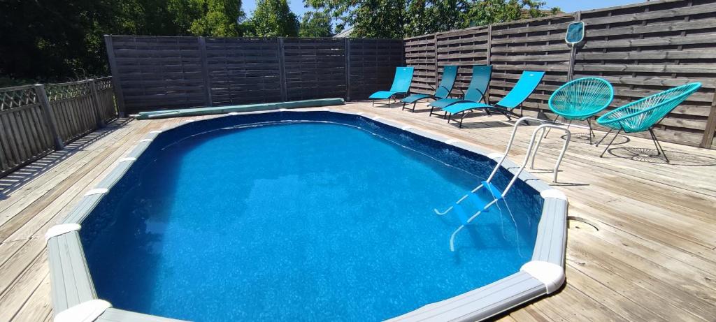 uma piscina com cadeiras azuis e um deque de madeira em Gîte du pré forestier em Saulxures-sur-Moselotte