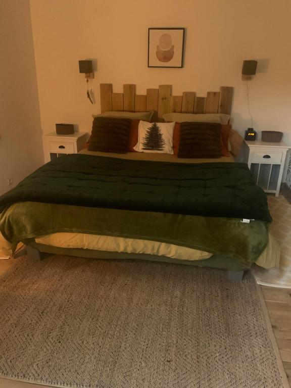 ein Schlafzimmer mit einem großen Bett und einer grünen Decke in der Unterkunft L Orée du Bois in Agnetz