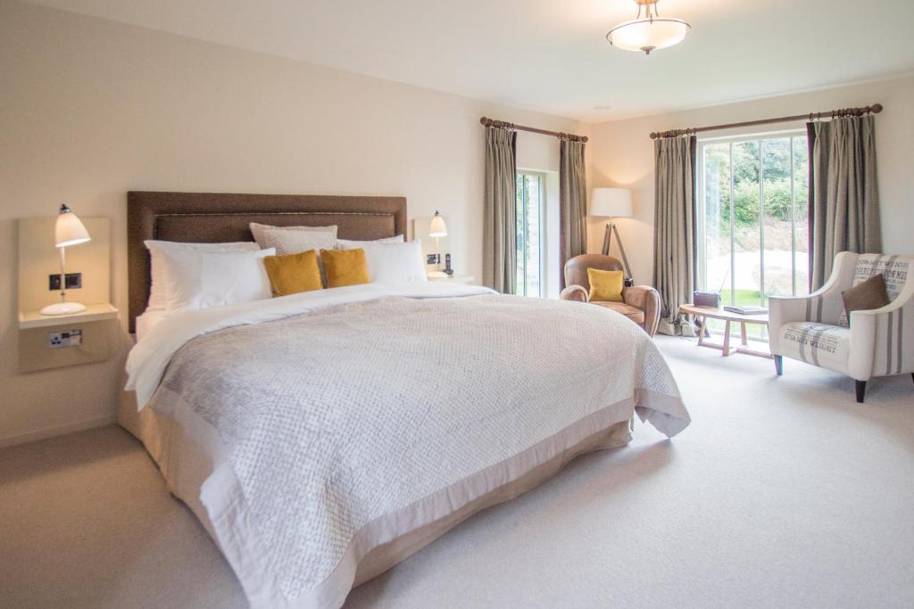 a bedroom with a large white bed and a chair at The Plume of Feathers in Mitchell