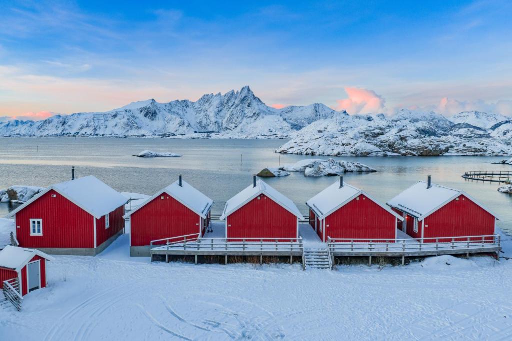レクネスにあるStatles Rorbu- og Konferansesenter ASの雪の中に山々が見える赤い家々