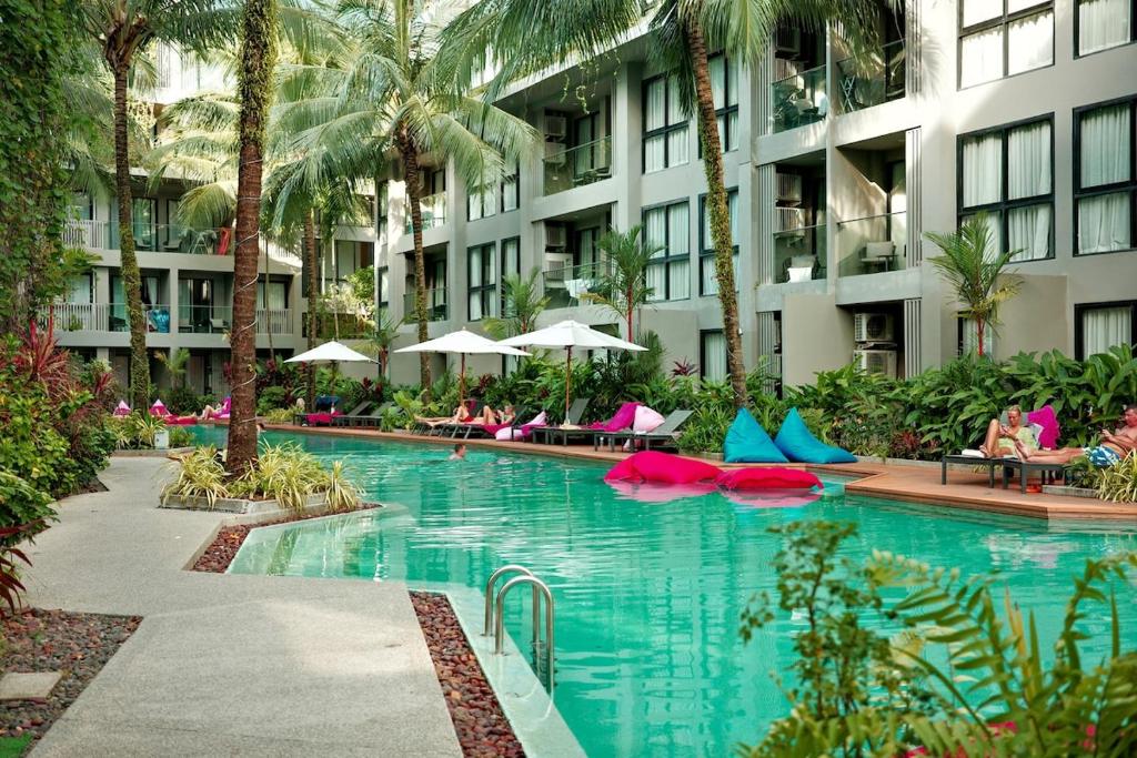 ein Schwimmbad in einem Hotel mit Menschen, die auf Stühlen sitzen in der Unterkunft Stylish apartment close to Bang Tao beach in Strand Bang Tao