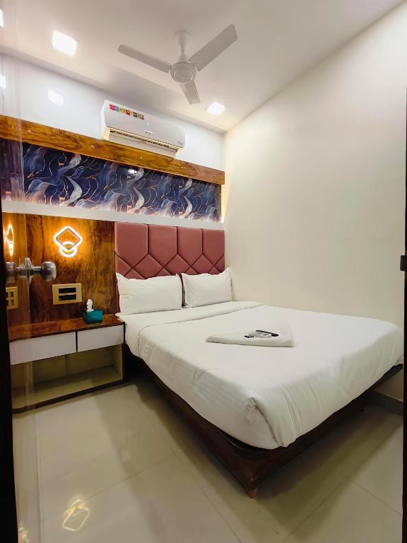 a bedroom with a white bed with a red headboard at Hotel M R STAY in Mumbai