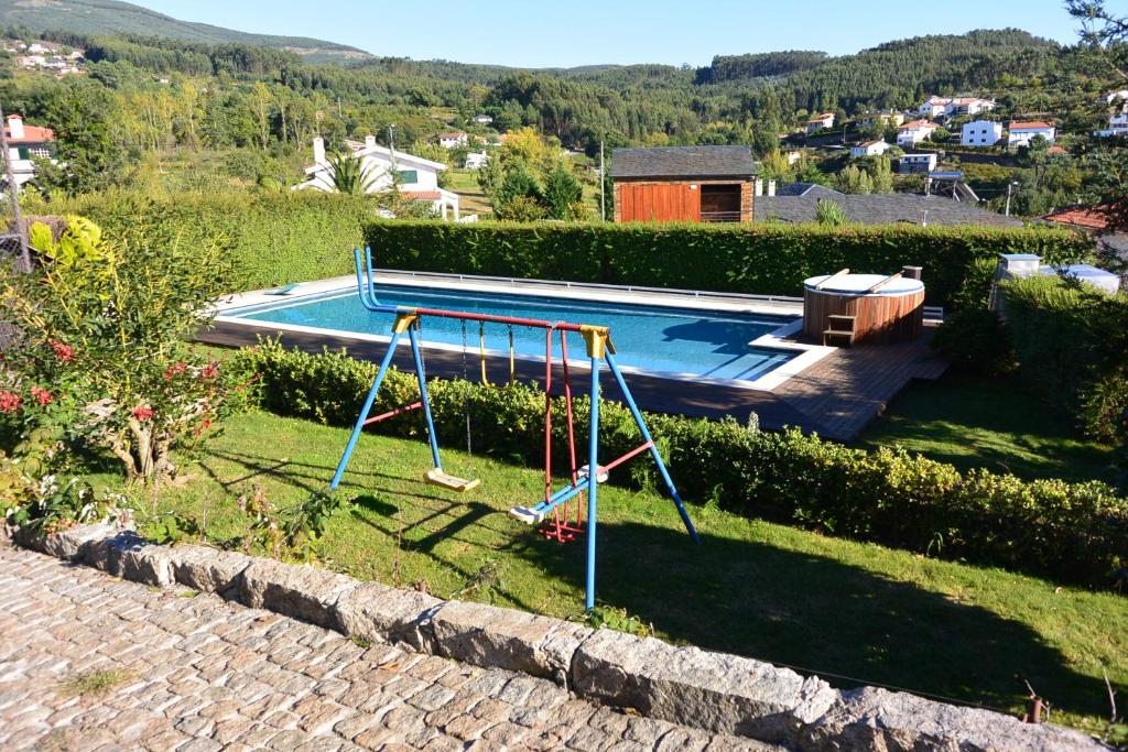a swimming pool with a swing in a yard at Casa do Lagar in Alvarenga
