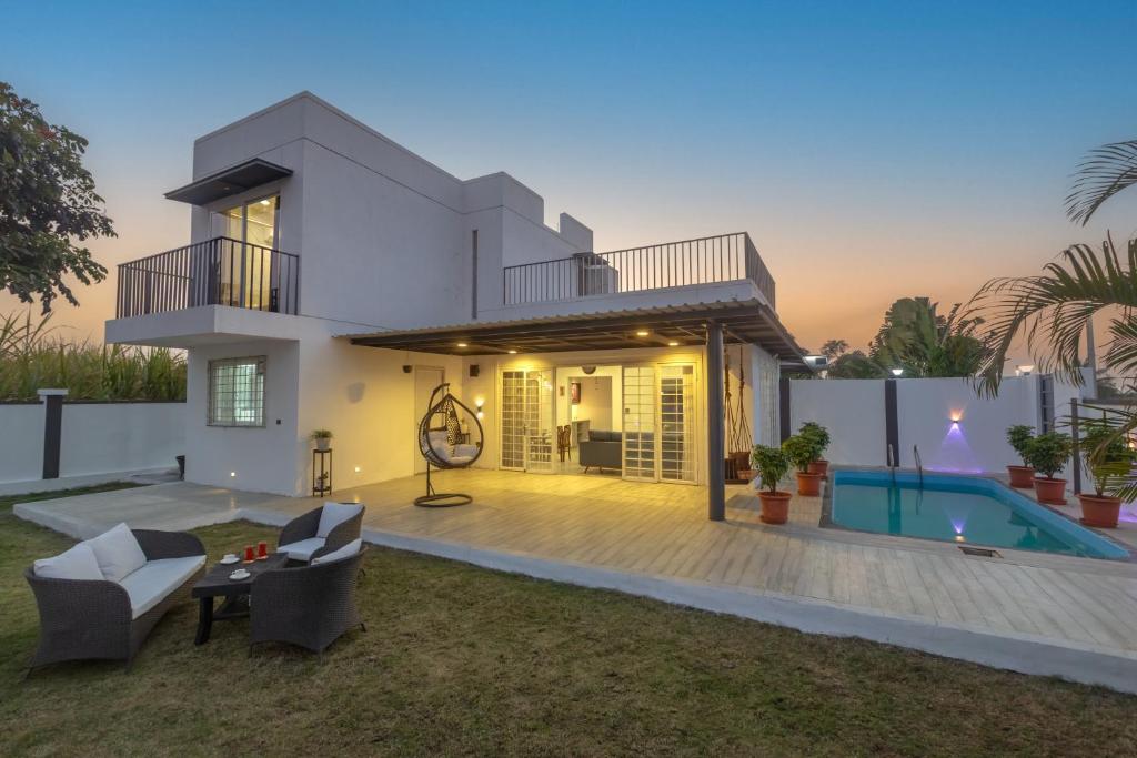 a villa with a swimming pool at dusk at SaffronStays Palash in Ane