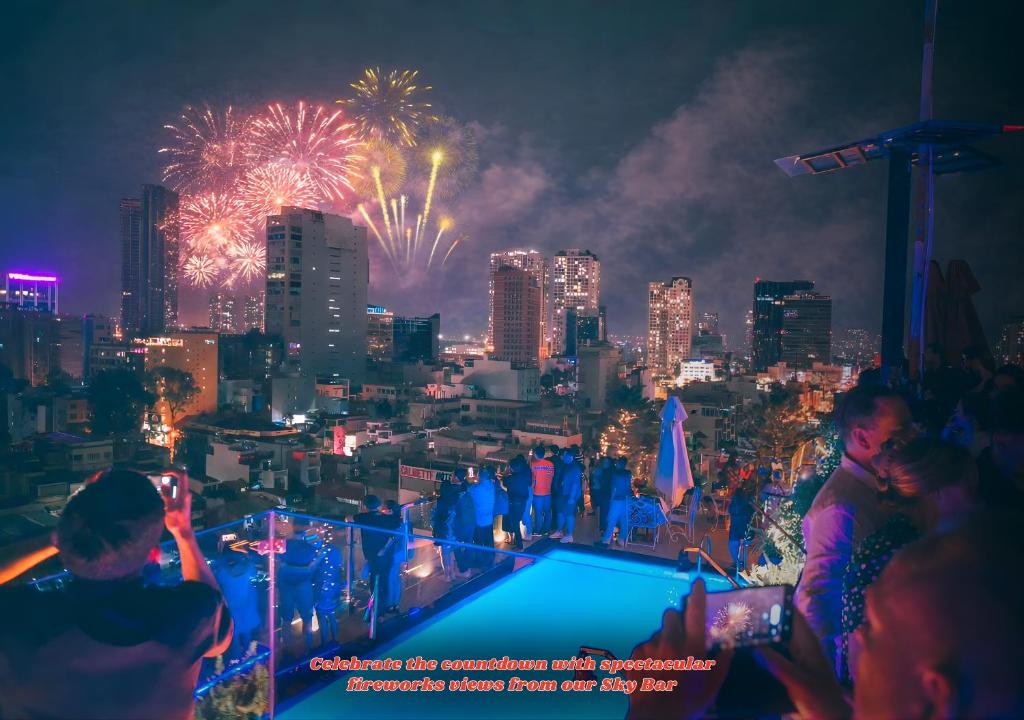胡志明市Happy Life Grand Hotel & Rooftop Skybar的一群人站在屋顶上观看烟花