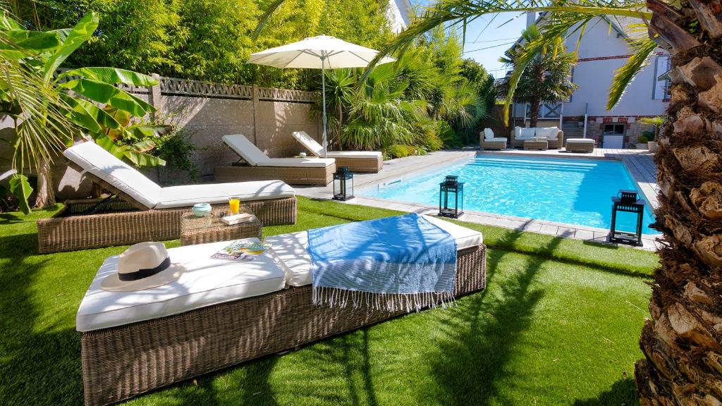 a backyard with a pool with chairs and a table at Villa la Ruche in La Baule