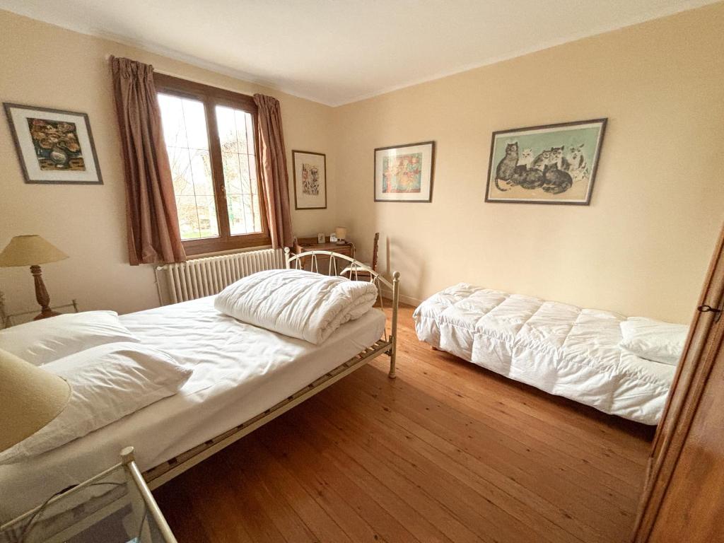 ein Schlafzimmer mit zwei Betten und einem Fenster in der Unterkunft Maison avec jardin dans le centre de Cabourg in Cabourg
