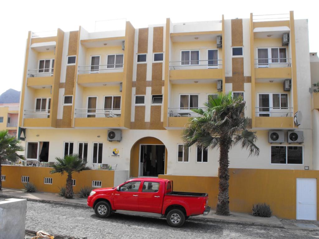 un camión rojo estacionado frente a un edificio en Hotel Lazareto en Mindelo