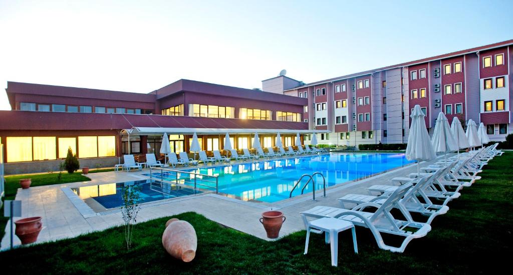 un hotel con piscina con sedie e ombrelloni di Crystal Kaymakli Hotel & Spa a Kaymaklı