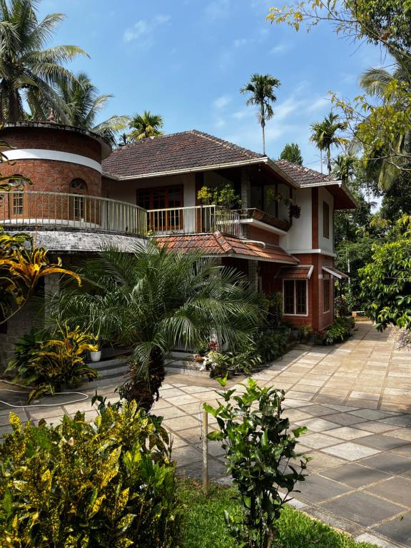 a house with palm trees in front of it at Avocado Orchards - Home Stay in Kenichira