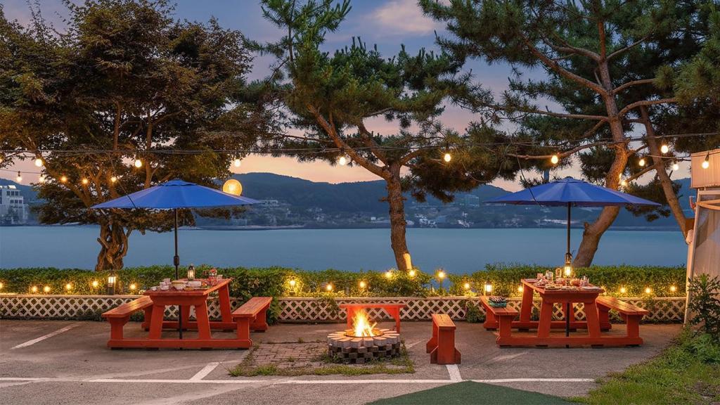 een terras met tafels en parasols en een open haard bij Daebudo green beach Pension in Ansan