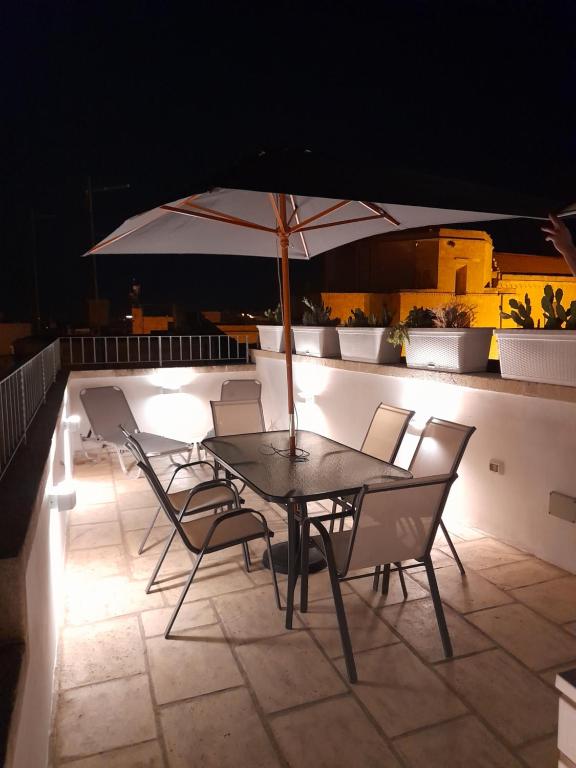 een tafel en stoelen met een parasol op een dak bij Casa Ninu' in Maruggio