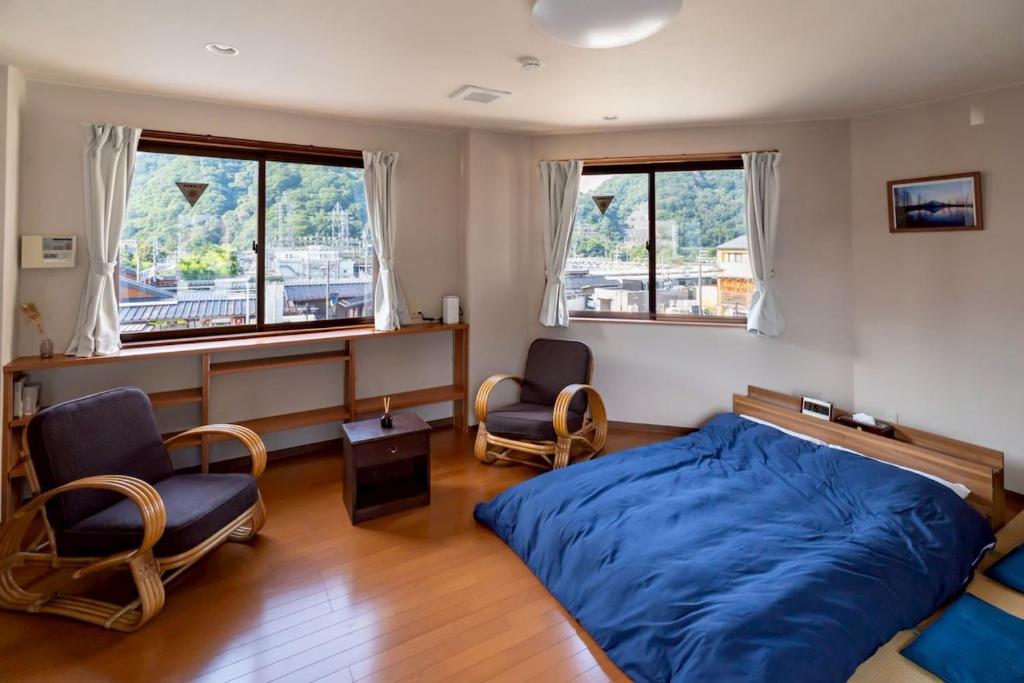 a bedroom with a bed and two chairs and windows at Otsuki in Oishi