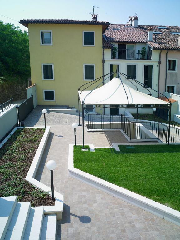 a patio with a large white umbrella and grass at Corte Trambai in Gambellara