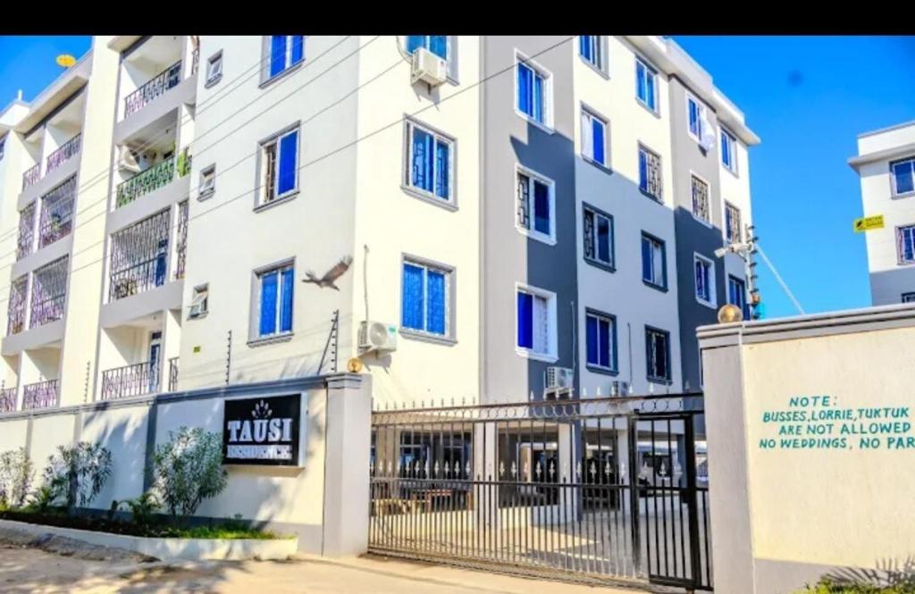 een groot wit gebouw met een bord ervoor bij Tausi Home in Mombasa