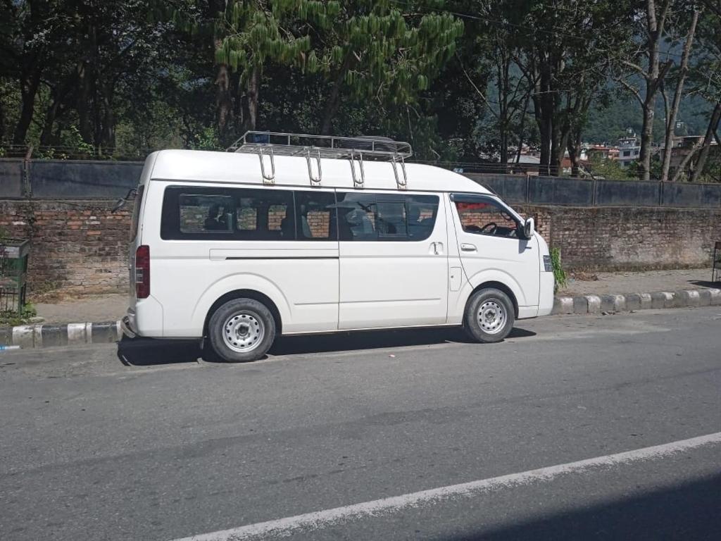 a white van parked on the side of a street at 12 seater micro van EV in Kathmandu